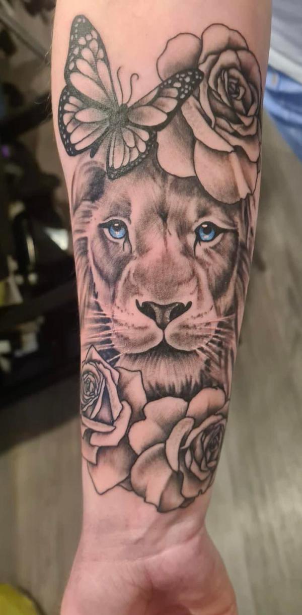 Lioness with roses and butterfly forearm tattoo