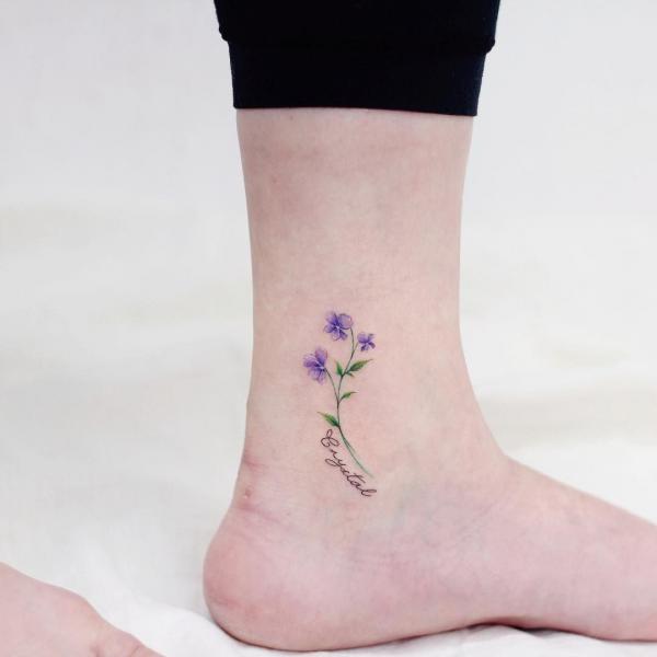 Minimalist violet flower with name ankle tattoo