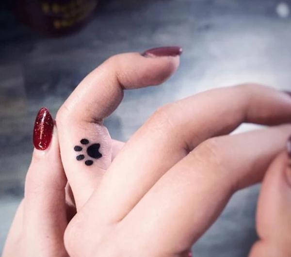Paw print tattoo on side of finger