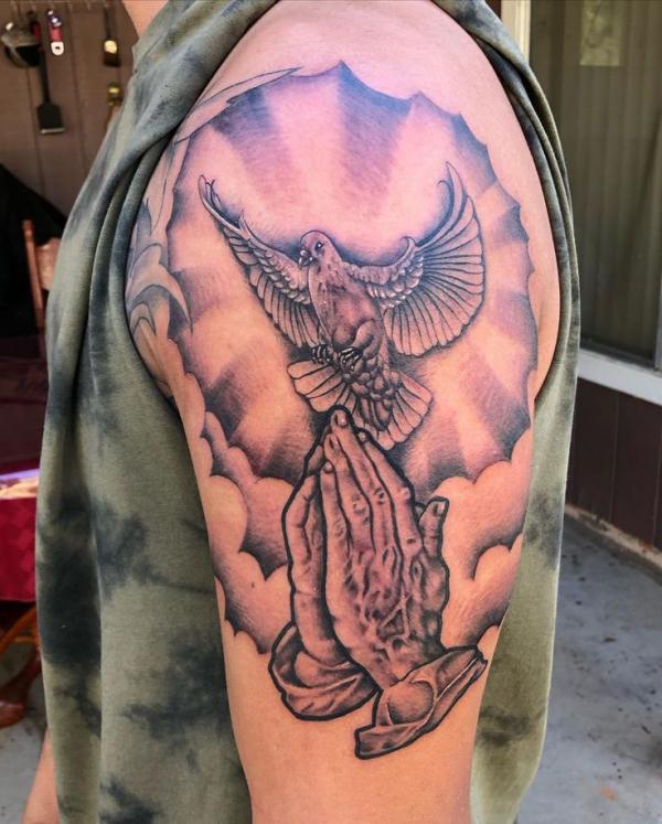 Praying hands and dove with clouds tattoo on upper arm
