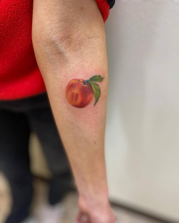 Realistic peach tattoo on forearm 1