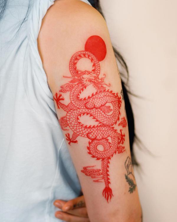 Red dragon and sun tattoo on upper arm