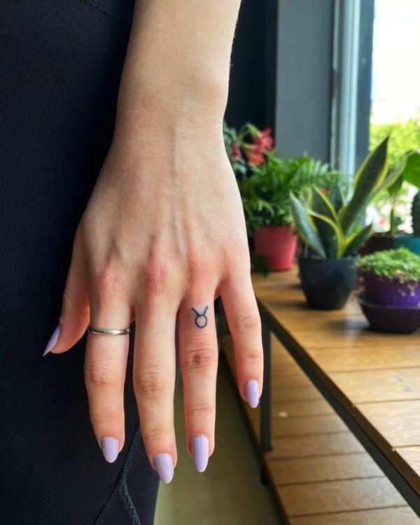 Simple Taurus Glyph tattoo on ring finger