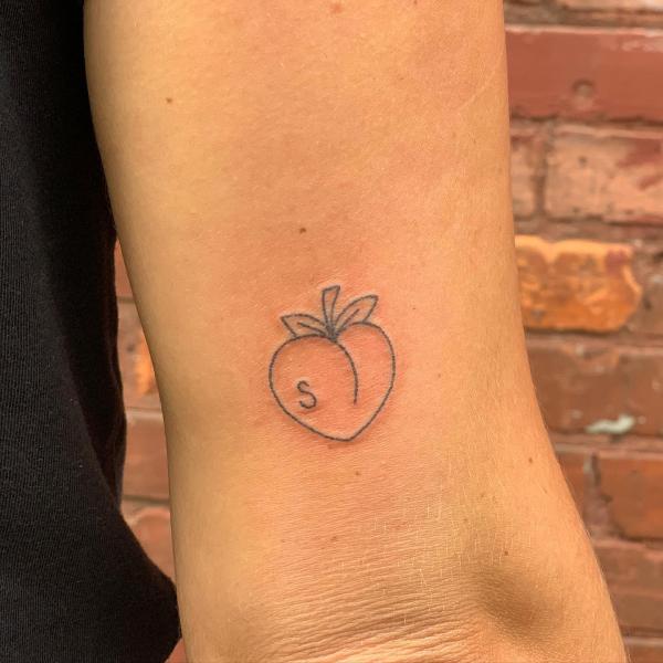 Simple peach tattoo above elbow