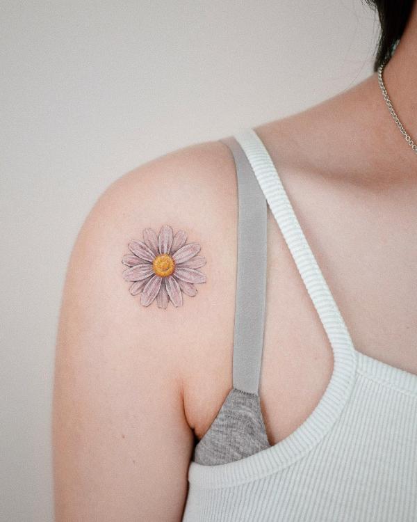 Single white daisy tattoo on shoulder