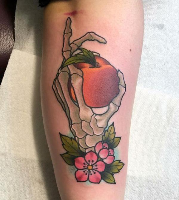 Skeleton hand holding a peach tattoo