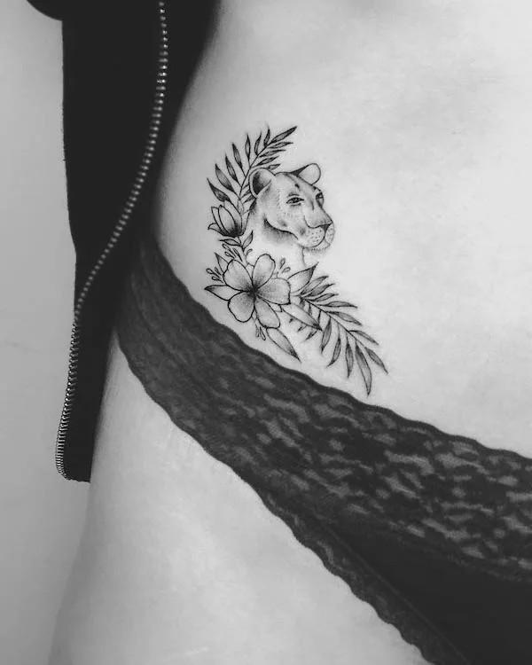 Small lioness with fern and flower bikini line tattoo