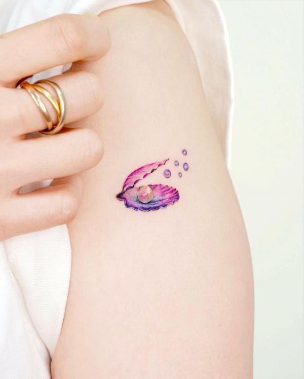 Small shell with pearls upper arm tattoo
