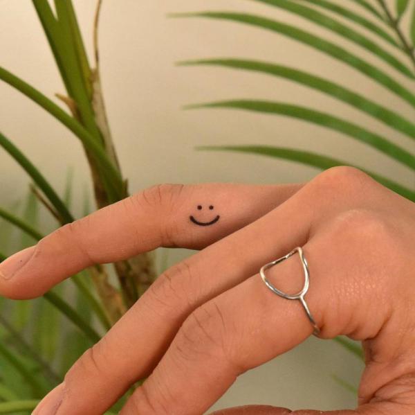 Smiley face finger tattoo