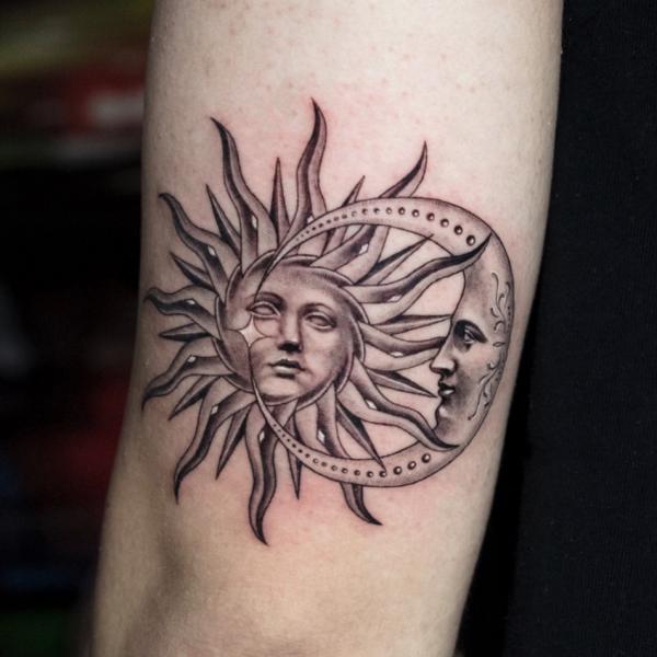 Sun and moon faces upper arm tattoo