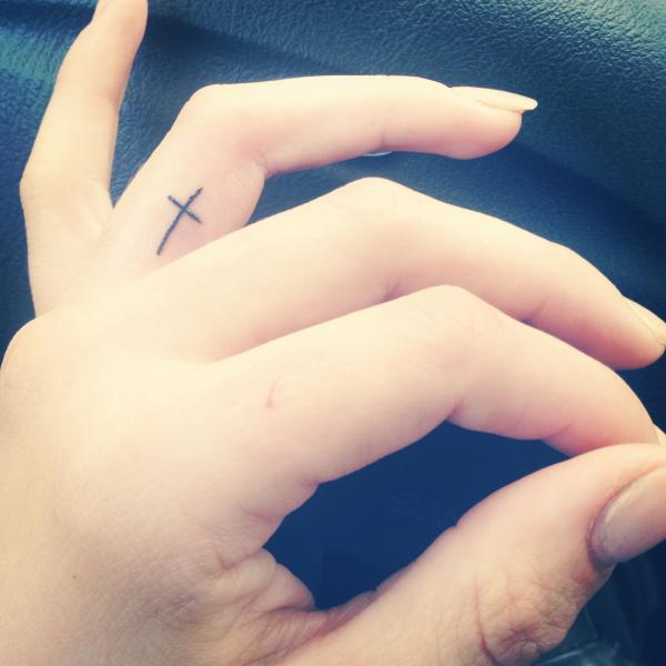 Tiny cross ring finger tattoo