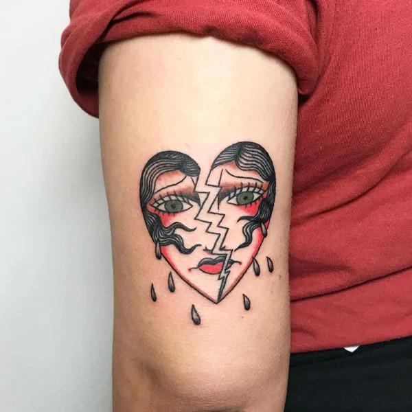 Traditional broken heart 2 faces tattoo above elbow