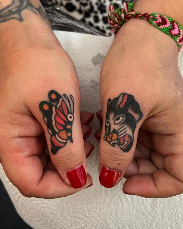 Traditional butterfly and panther tattoos on both thumb fingers