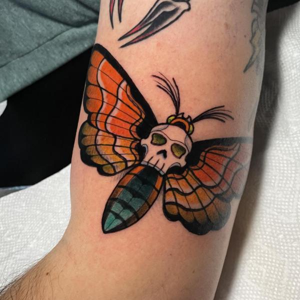 Traditional death moth tattoo on upper arm