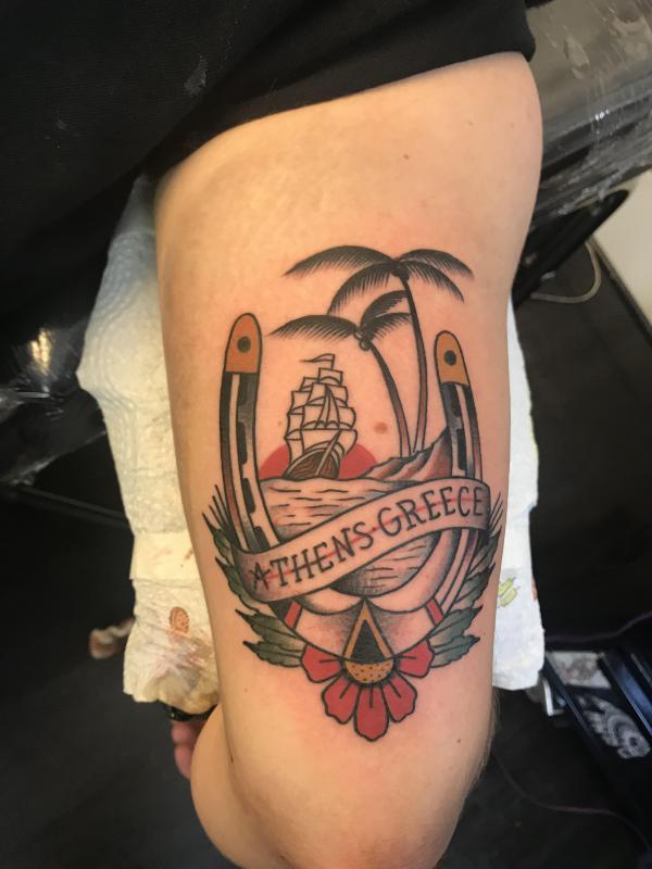 Traditional horseshoe and ship with palm tree upper arm tattoo
