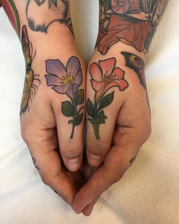 Violet flowers matching tattoos on thumbs
