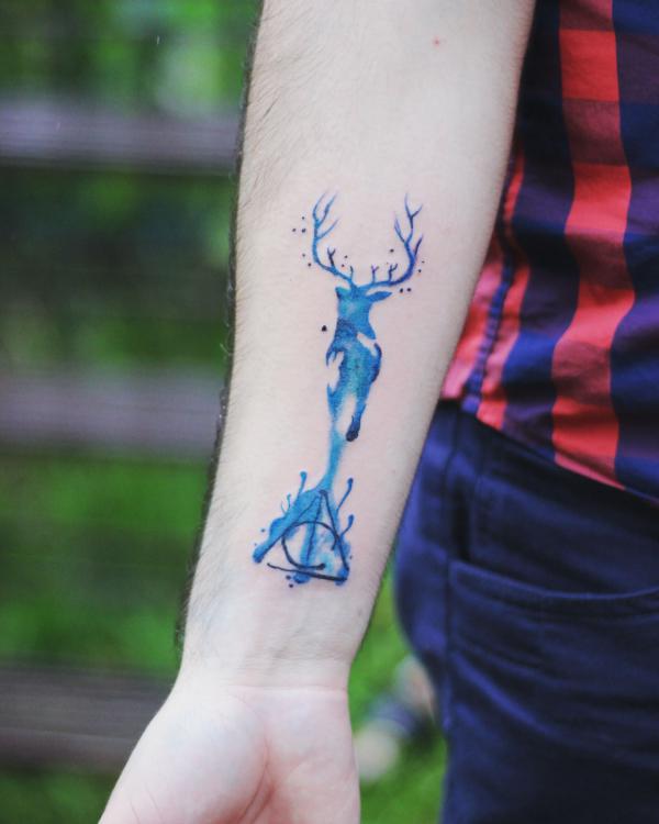 Watercolor patronus stag and deathly hallows tattoo on forearm