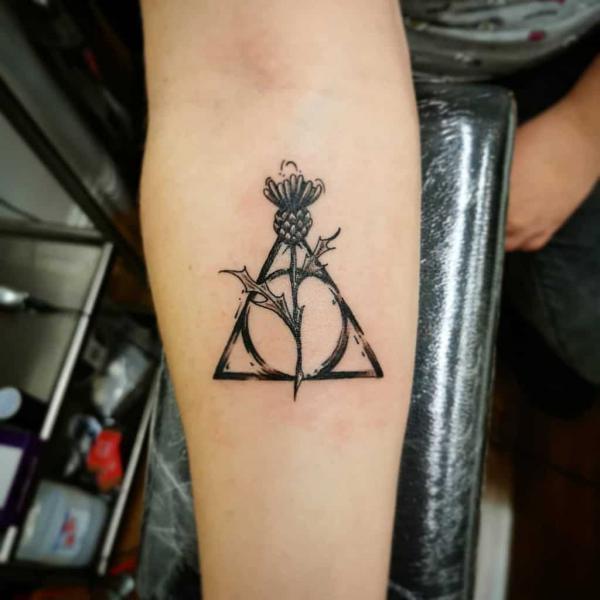 deathly hallows and thistle tattoo on forearm