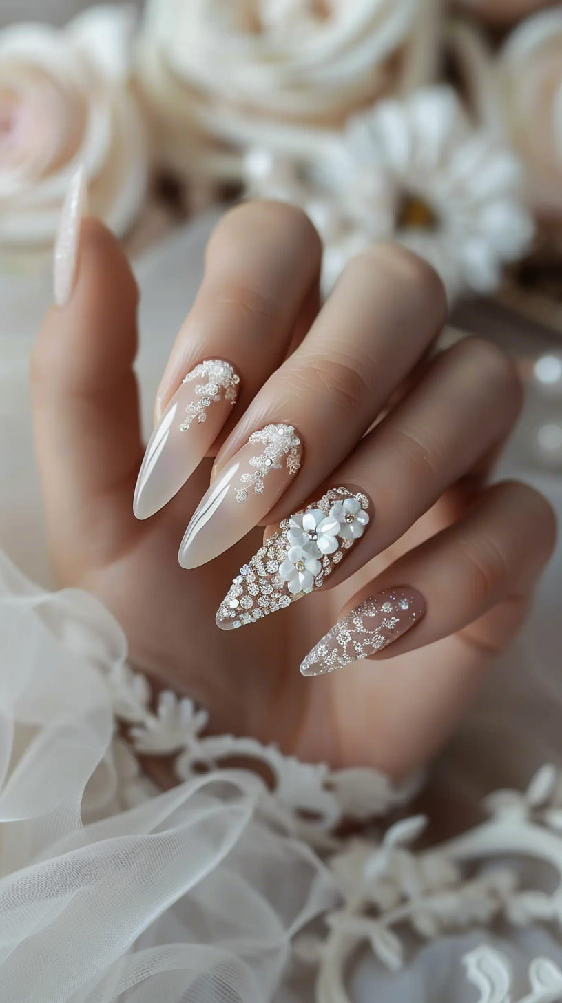 Stiletto nails with a sheer base, adorned with intricate white lace patterns and sparkling crystals, culminating in a dramatic white floral accent on the ring finger, perfect for a bride's special day.