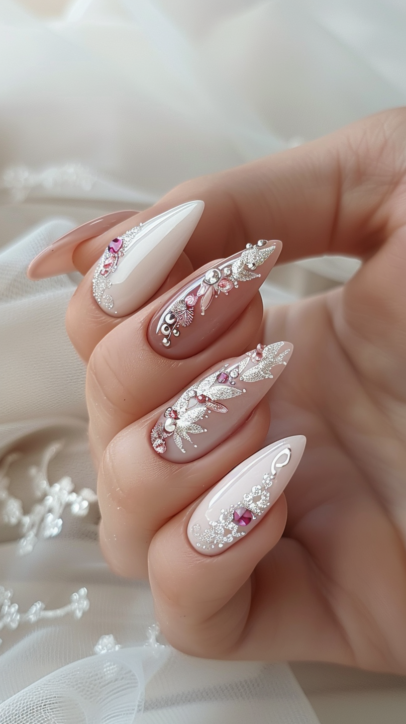 Stiletto bridal nails with a pale pink base adorned with silver glitter, delicate white floral accents, and pink gemstones, providing an elegant and feminine touch suitable for a wedding.
