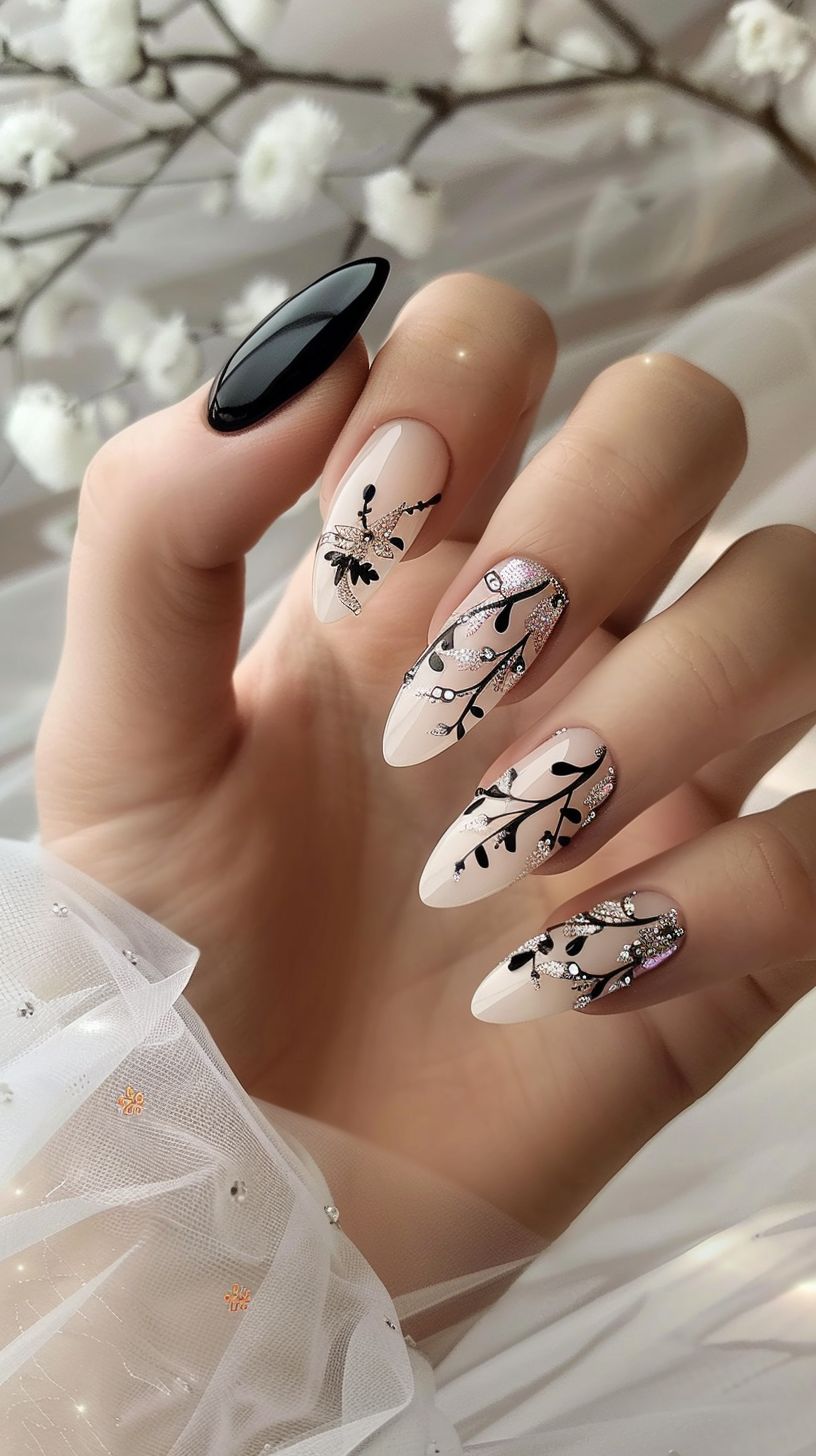 The bridal nails feature a striking black and white design with intricate branch and leaf patterns accented by shimmering rhinestones. The nude base provides an elegant contrast, while the almond shape elongates the fingers.