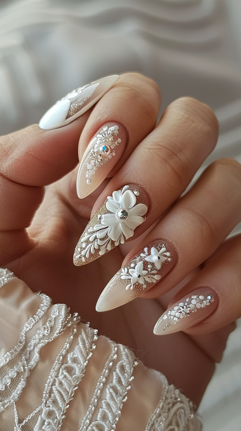 The image showcases a stunning bridal nail design featuring intricate white floral embellishments and gemstones on a nude base. The elongated almond-shaped nails are adorned with pearly 3D flowers, shimmering rhinestones, and delicate beadwork that exudes elegance and sophistication