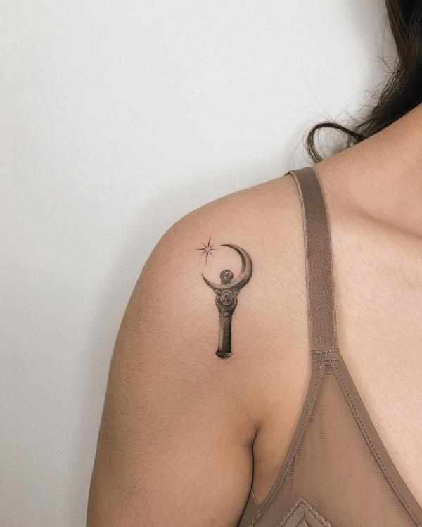 Minimalist sailor moon wand tattoo on shoulder