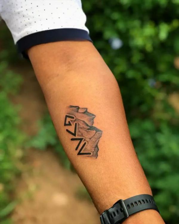 god is greater than the highs and lows with mountain tattoo on forearm