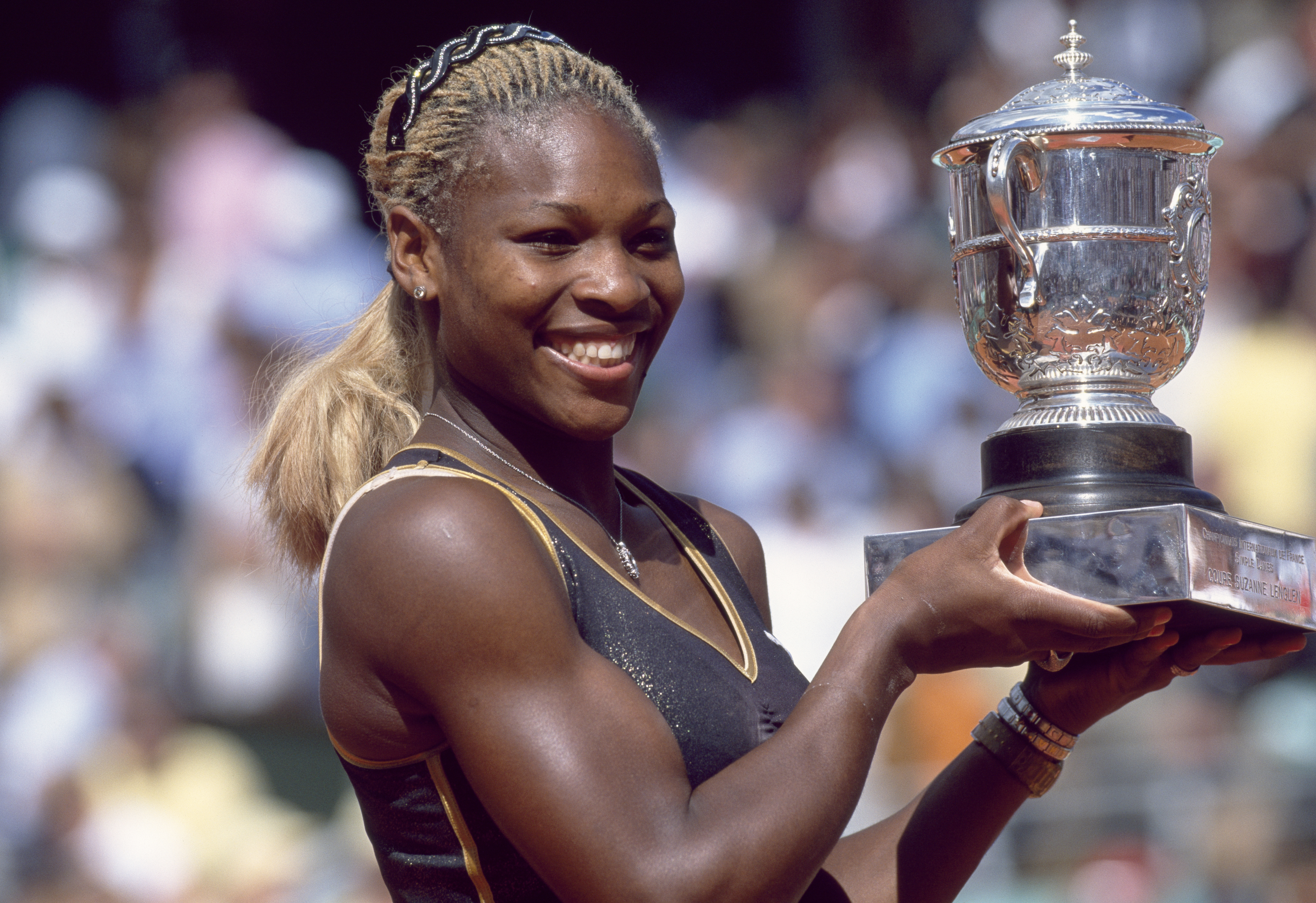 Serena Williams smiles and poses with her trophy after defeating her sister Venus Williams in the Women's Singles Final of the French Open Tennis Championships at the Stade Roland Garros on June 8, 2002, in Paris, France.