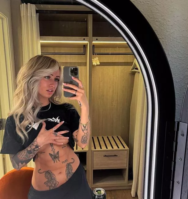 Model Essie lifts up her T-shirt and she shows off her tattoos