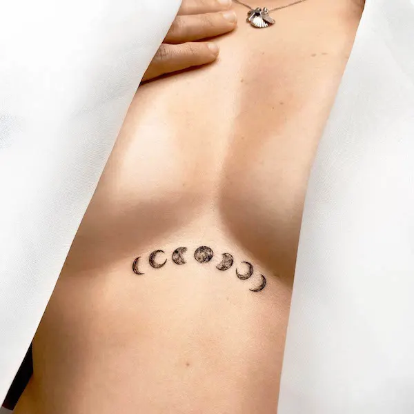 Small moon phase underboob tattoo by @1991.ink_