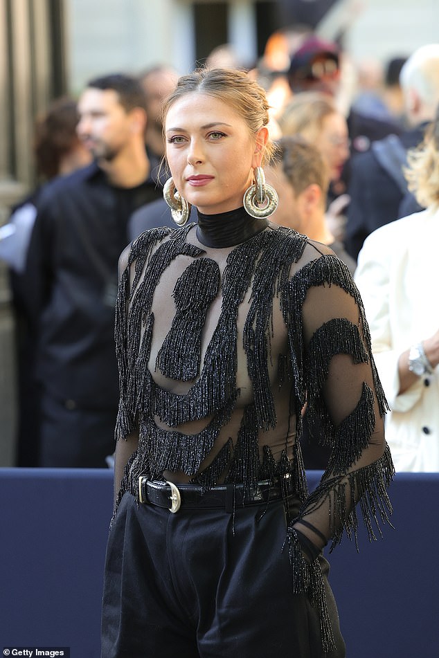 She looked the picture of elegance, showing flashes of skin through a sheer high-neck top with long sleeves, featuring sparkly black and silver tassels